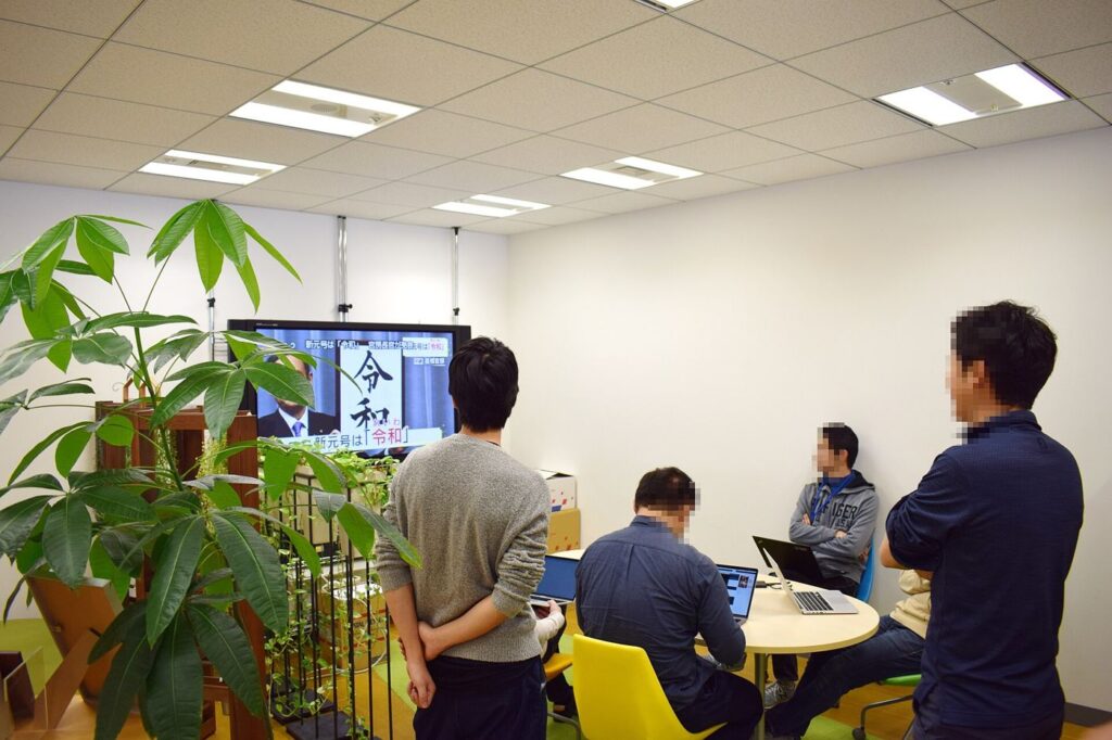 Office workers use laptops at shared desks during a collaborative working day.